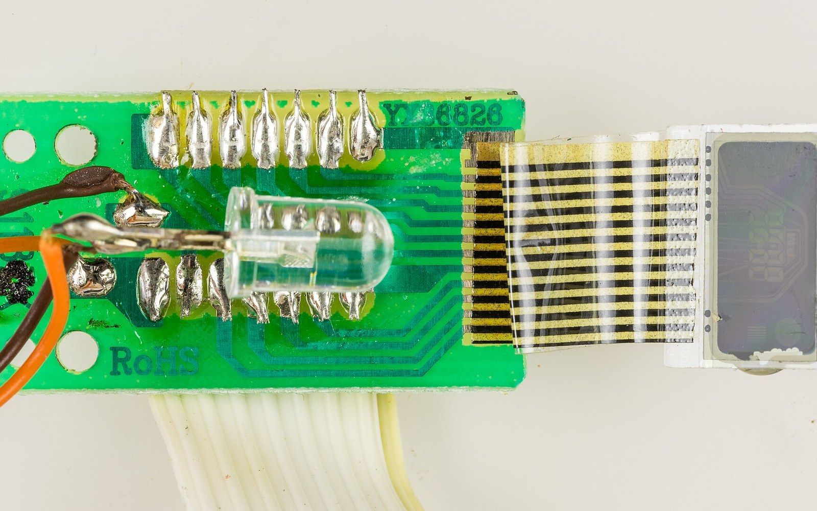 A bare printed circuit board with a ribbon cable attached